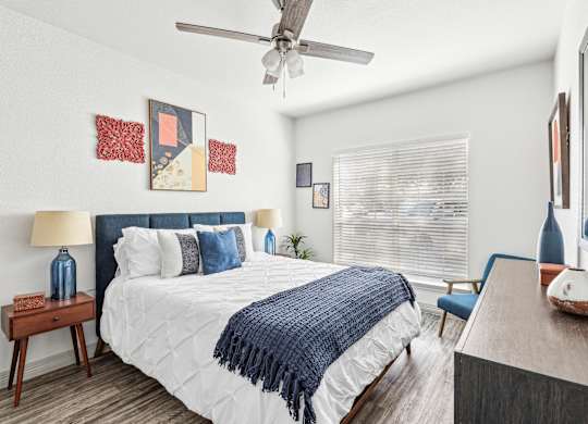 A bedroom with a bed, a ceiling fan, and a chair.