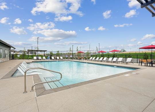 A large swimming pool with a diving board and lounge chairs.