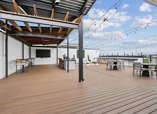 A wooden deck with tables and chairs and string lights.