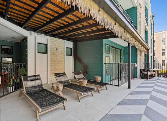 A patio with a striped rug and two lounge chairs.