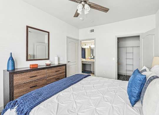 A bedroom with a large bed and a ceiling fan.