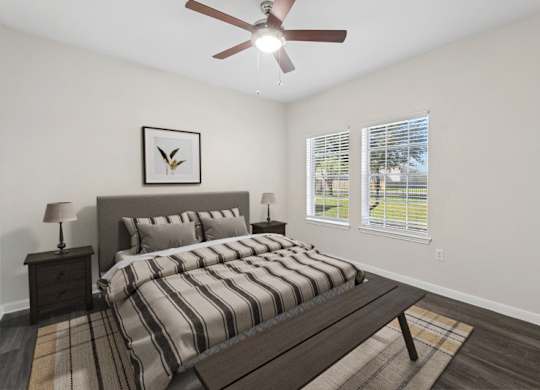A bedroom with a bed, nightstand, and a ceiling fan.