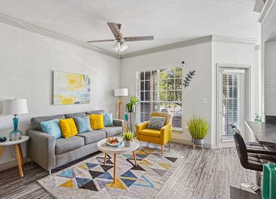A living room with a grey couch, yellow chair, and a painting on the wall.