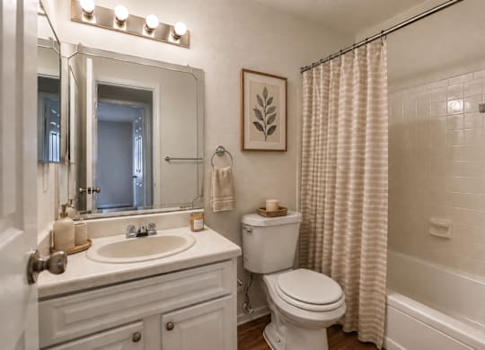 A white bathroom with a toilet, sink, and shower.