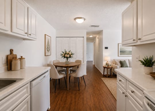 A kitchen with white cabinets and a wooden floor.