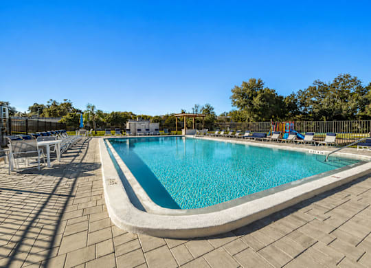 A large outdoor swimming pool surrounded by a tiled patio.