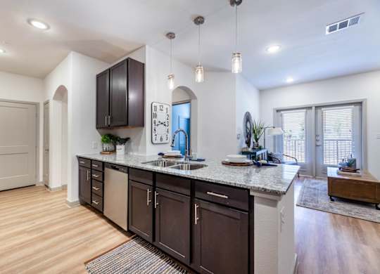 A kitchen with dark brown cabinets and a granite countertop.