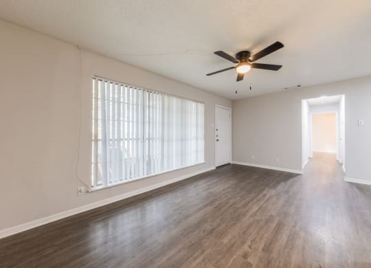 an empty living room with a ceiling fan