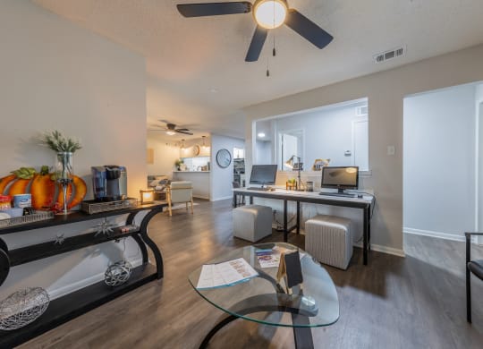 a living room with a ceiling fan and a desk with a computer