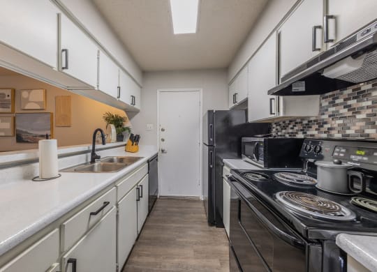 a kitchen with white cabinets and black appliances