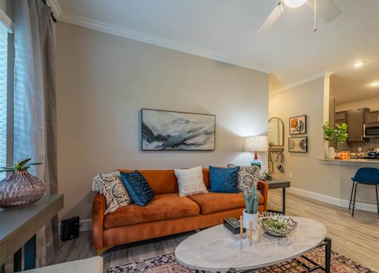 a living room with a couch coffee table and a kitchen in the background