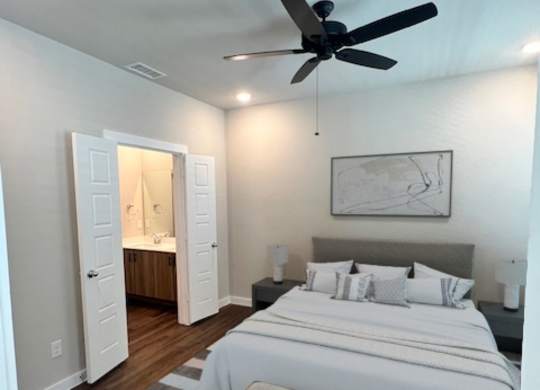 A bedroom with a large bed and a ceiling fan.