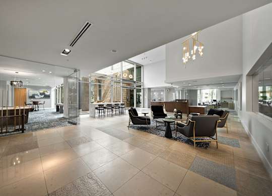 a large lobby with chairs and tables and glass walls