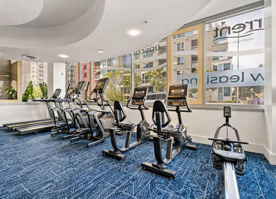 a gym with cardio equipment and weights on a blue rug