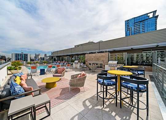 a rooftop patio with tables and chairs and a city in the background