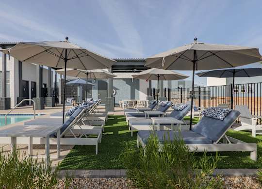 A poolside area with sun loungers and umbrellas.