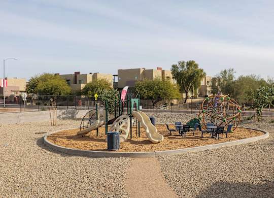A playground with a yellow slide and a green tree.