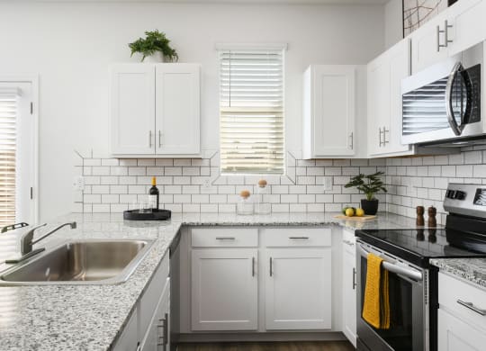 a kitchen with white cabinets and granite counter tops and a sink