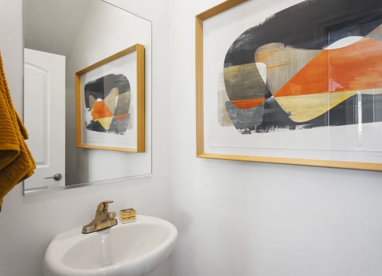 two paintings and a sink in a bathroom with a mirror