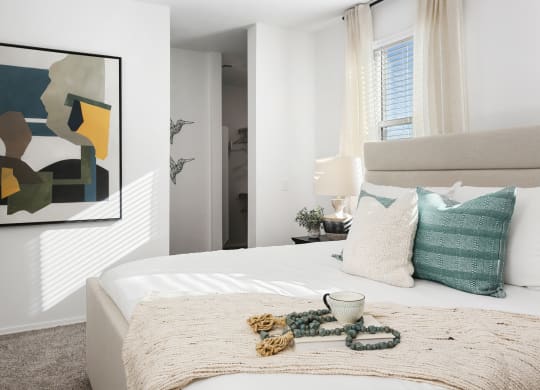 a bedroom with a bed and pillows and a painting on the wall