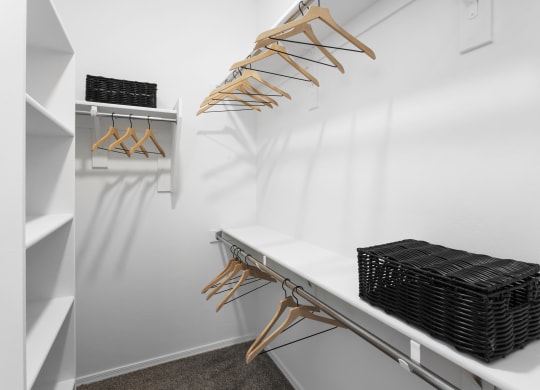 a walk in closet with a white wall and a shelf with wicker baskets