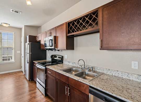 A kitchen with brown cabinets and a black fridge.