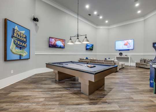 A room with a pool table and a TV mounted on the wall.