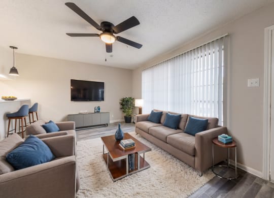 a living room with couches and a coffee table and a ceiling fan