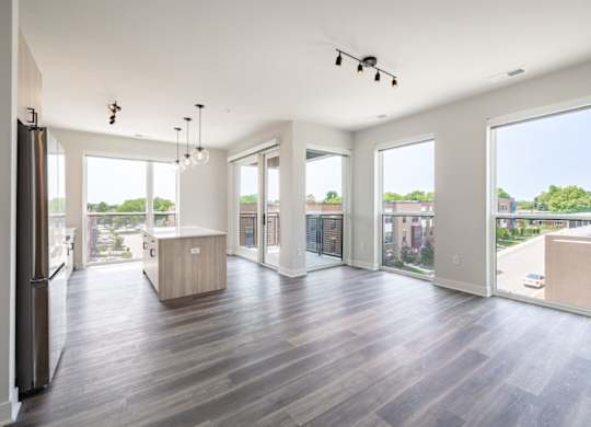 A spacious, empty room with wood flooring and large windows.