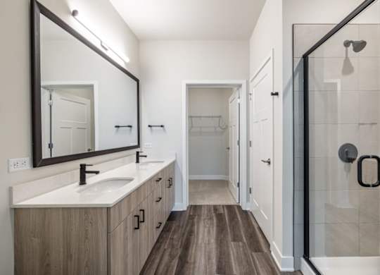 A bathroom with a sink, mirror, and shower.