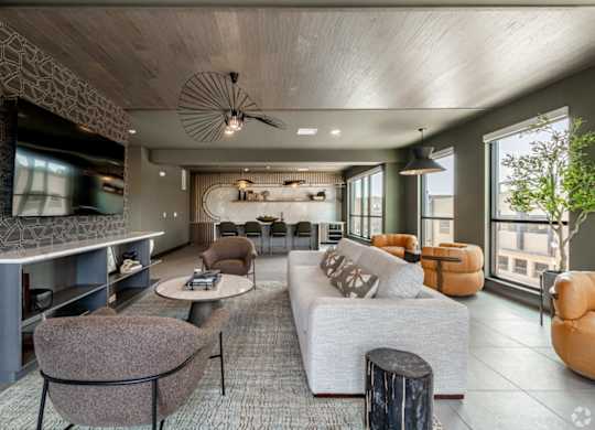 A modern living room with a grey sofa, a brown armchair, and a wooden ceiling.