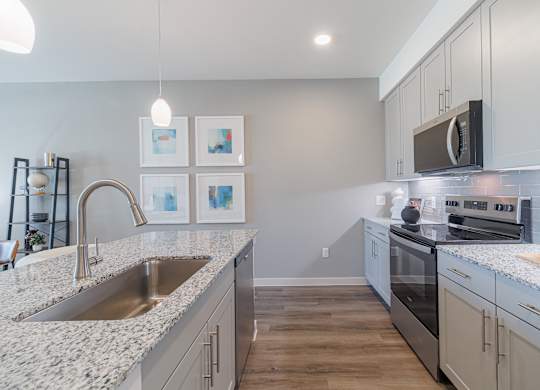 A kitchen with a sink, stove, and cabinets.