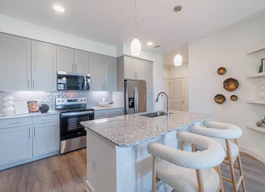 A kitchen with a granite countertop and white bar stools.