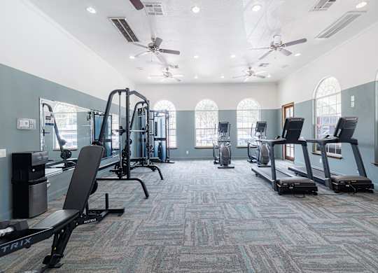A spacious gym with a variety of equipment and a carpeted floor.