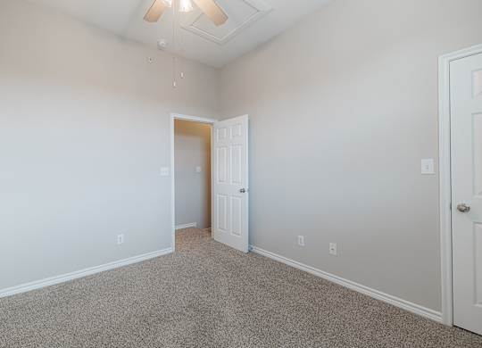 A room with a carpeted floor and a ceiling fan.