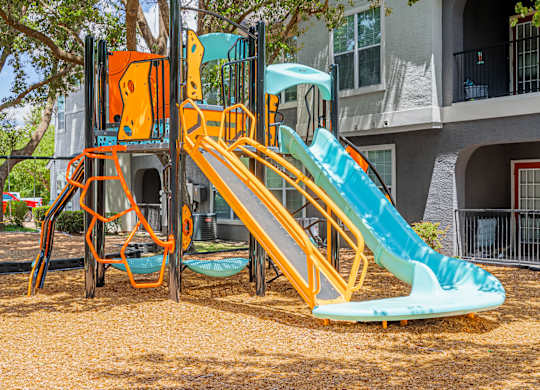 A playground with a yellow slide and a green slide.