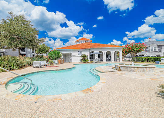 A pool with a slide and a building in the background.