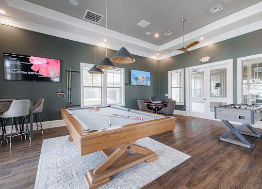 A room with a pool table and a TV mounted on the wall.