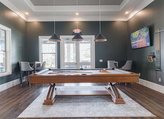 A room with a pool table and a television mounted on the wall.