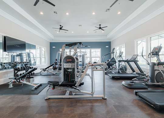 A gym with a variety of exercise equipment including treadmills, elliptical machines, and a weight machine.