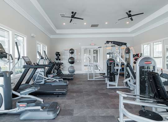 A spacious gym with a variety of equipment including treadmills, elliptical machines, and weight machines.