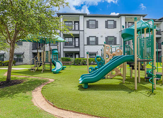 A playground with a green slide and a wooden structure.