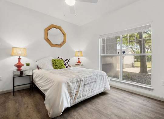 A bedroom with a bed, two lamps, and a mirror on the wall.