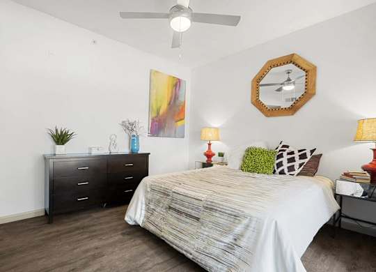 A bedroom with a bed, dresser, and ceiling fan.