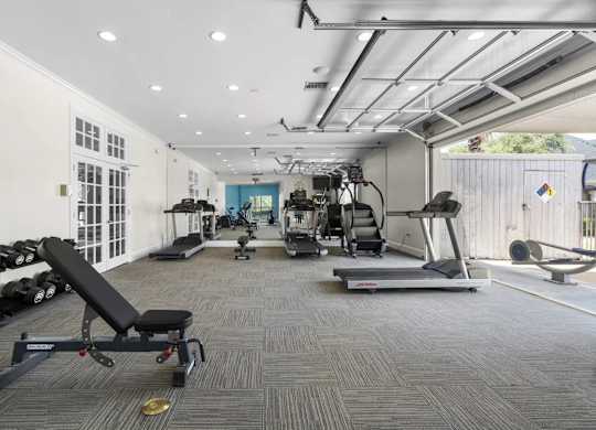A gym with a variety of equipment including a treadmill, weights, and a bench press.
