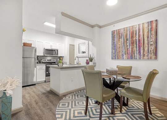 A kitchen with a dining table and chairs.