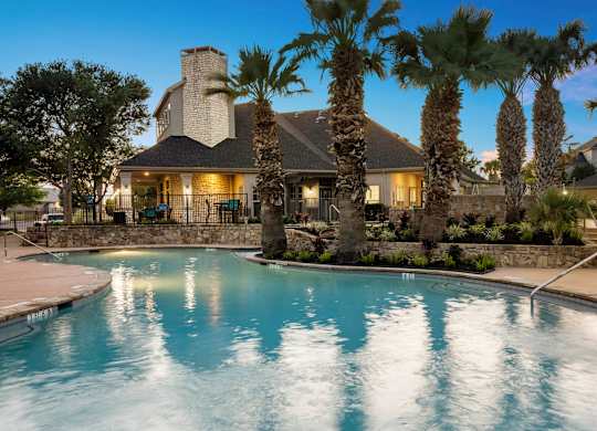 A house with a pool surrounded by palm trees.