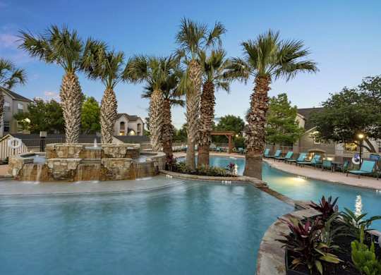 A pool surrounded by palm trees and a waterfall.