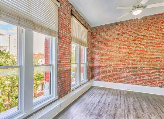 an empty room with large windows and a red brick wall