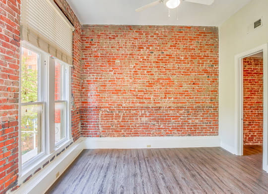 an empty room with hardwood floors and a brick wall